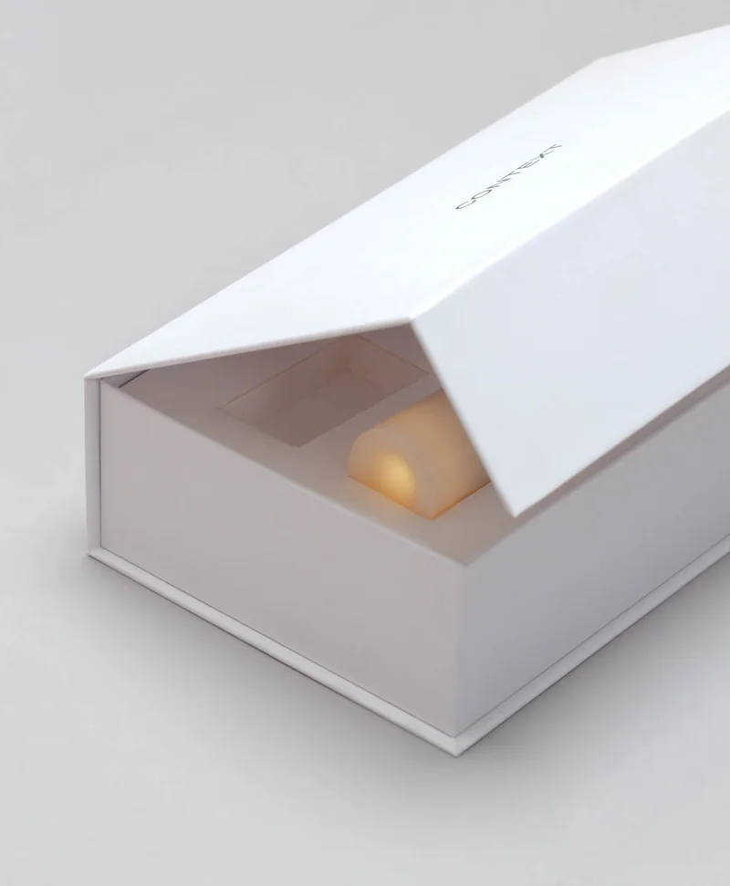 A warm, glowing Context candle beneath the lifted lid of its presentation box